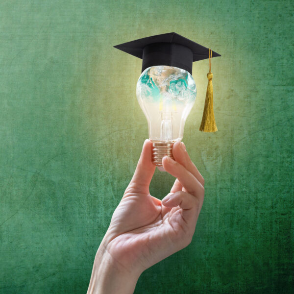 a hand holding a glass with a graduation cap and gown