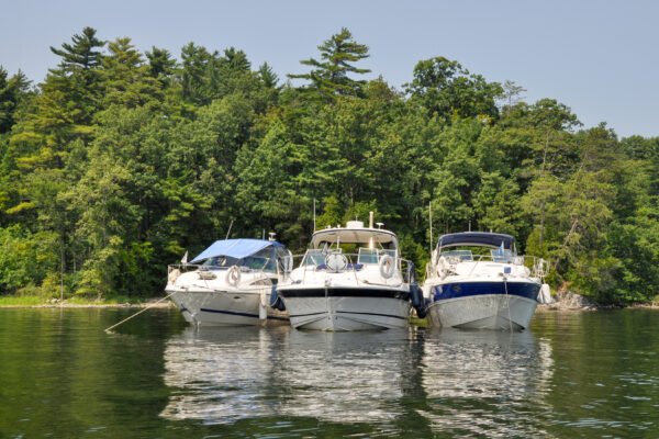 Panoramic view of three boats at anchor shoulder to shoulder in a bay